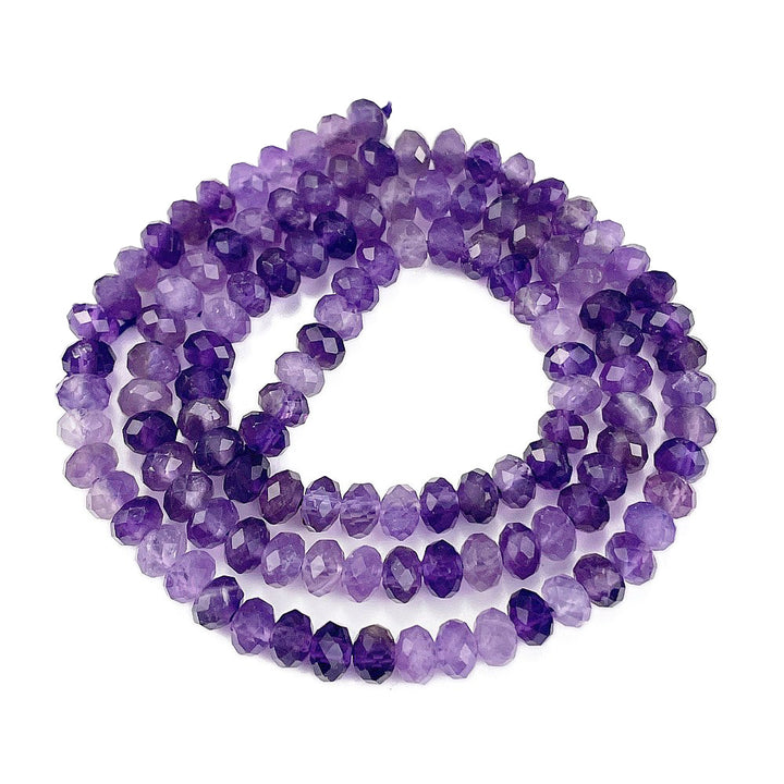Faceted purple amethyst beads coiled in a long strand on a plain white background.