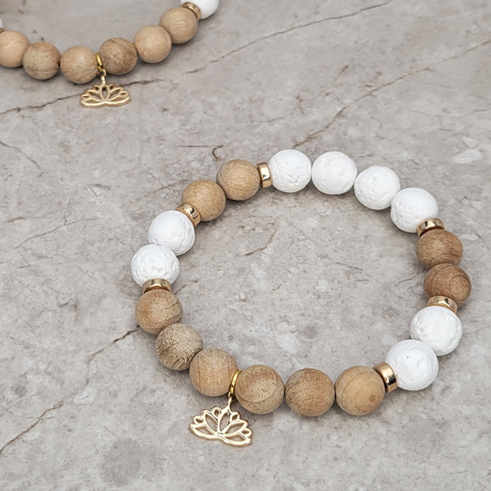 Accessorize your style with this Burlywood & White Lava Rock Beaded Bracelet! Featuring 10mm burlywood wooden beads, 10mm White Lava Rock Gemstone beads, 6mm light gold hematite disc spacer beads and 18K Gold Plated Lotus Charm. This beautiful beaded gemstone stretch bracelet is stackable, boho, and perfect for creating unique, eye-catching looks. Why not treat yourself today?  Size: 7.5" Inches