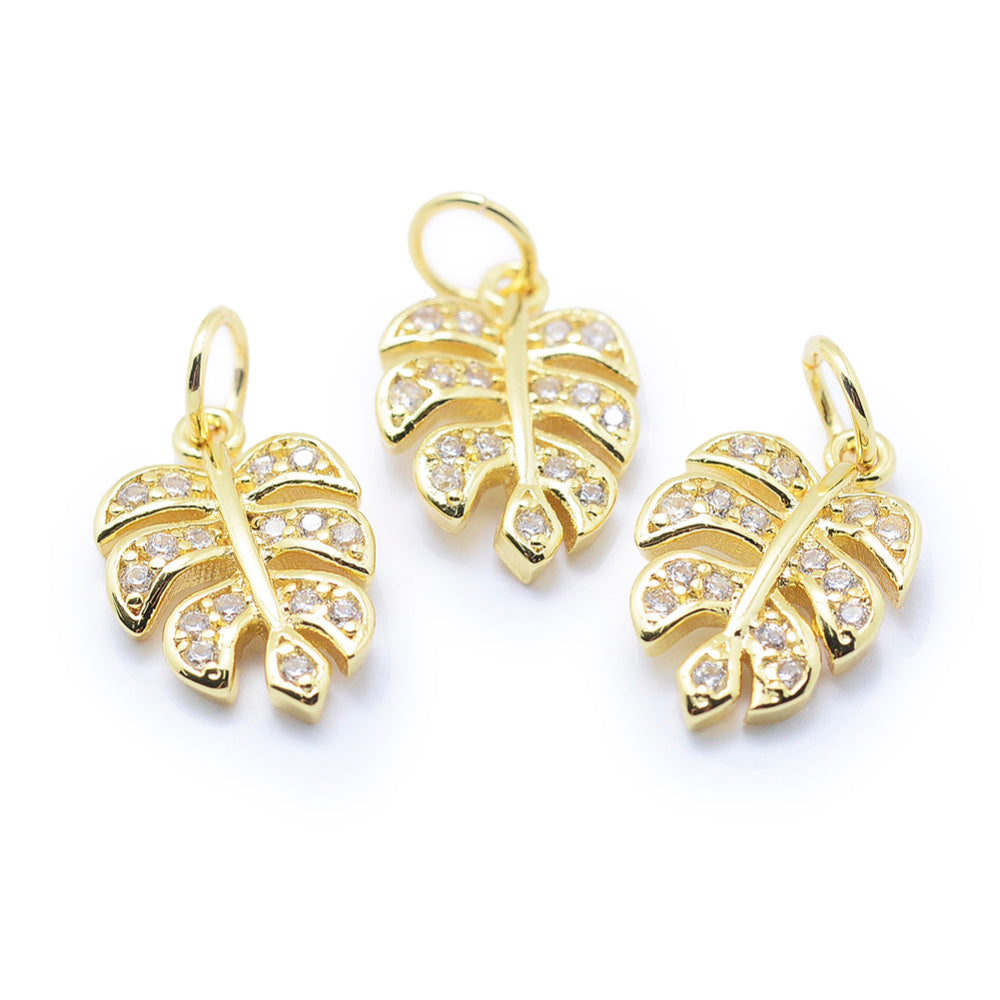 Tropical Leaf Charms, Brass Micro Pave Cubic Zirconia Clear & Gold Color Monstera Leaf Charms for DIY Jewelry Making.   Size: 14mm Length, 9mm Width, 2mm Thick, Hole: 3mm, Quantity: 1pcs/package.  Material: Cubic Zirconia Brass Micro Pave Tree Charm with Jump Ring. Gold Color.