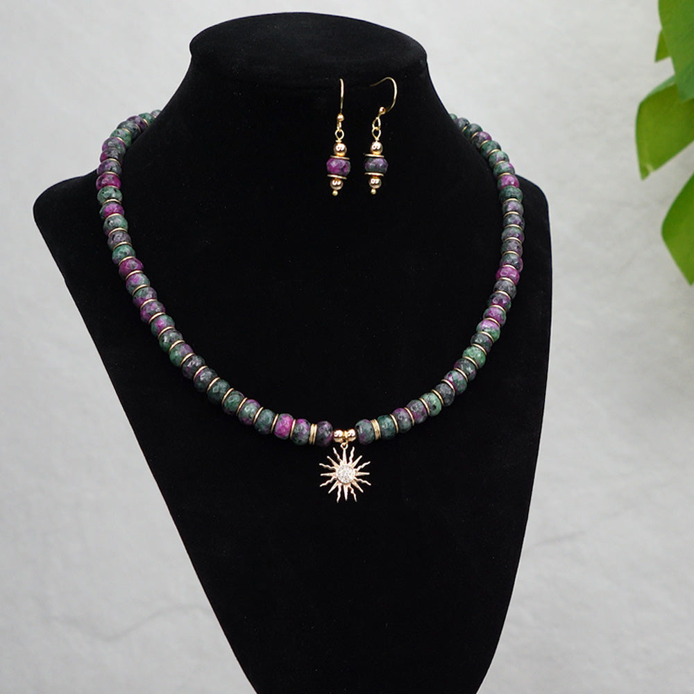 This Ruby Zoisite necklace set is a thing of beauty and elegance. Hand crafted with 8mm faceted rondelle beads, 18K Gold Plated disc spacer beads and a Cubic Zirconia Solar Eclipse Sun Charm, this stunning piece of jewelry is sure to captivate onlookers. 