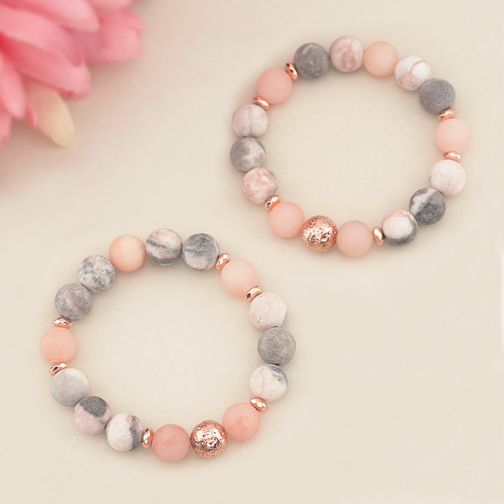 Two beaded bracelets with pink and gray beads on a light background