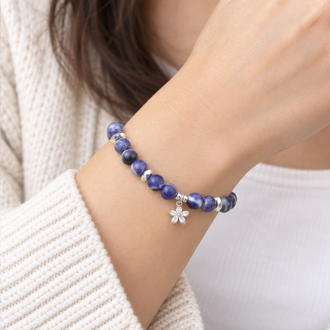 The Sodalite bracelet combines the deep, calming beauty of Sodalite beads with a silver cubic zirconia flower charm. Handcrafted to enhance intuition, promote emotional balance, and shield you from negativity, this piece is both a meaningful accessory and a stylish statement.