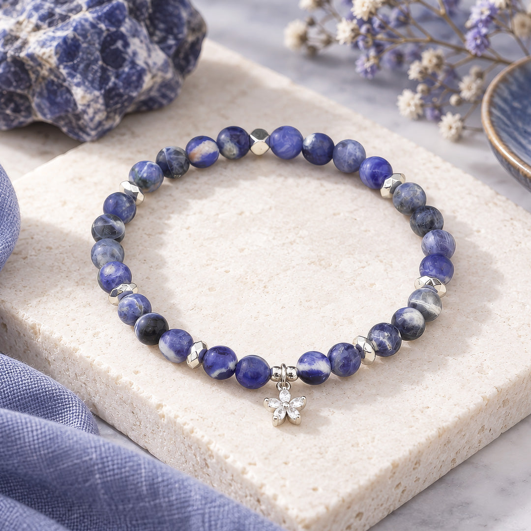 The Sodalite bracelet combines the deep, calming beauty of Sodalite beads with a silver cubic zirconia flower charm. Handcrafted to enhance intuition, promote emotional balance, and shield you from negativity, this piece is both a meaningful accessory and a stylish statement.