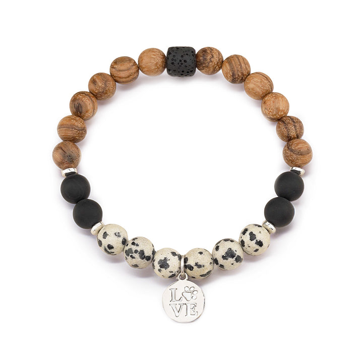Handcrafted bracelet featuring 8mm dalmatian jasper and lava rock beads paired with warm wooden accents. Finished with delicate 4mm hematite silver rondelles and a stainless steel love dog paw charm in silver. Stretchy design fits most wrists comfortably. Perfect for gemstone lovers and dog enthusiasts alike.
