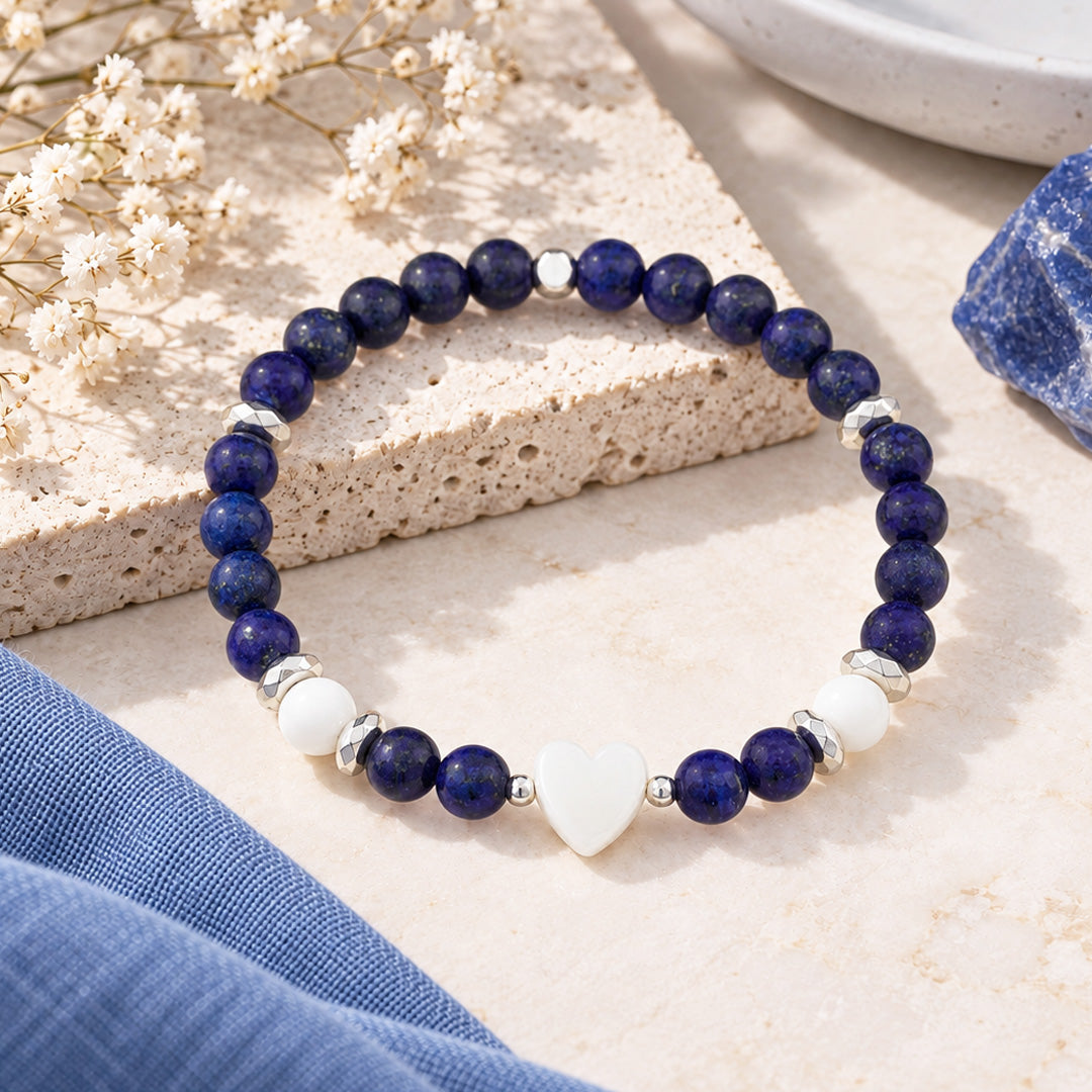 Embrace calm and elegance with this thoughtfully crafted beaded bracelet. Featuring radiant lapis lazuli and white jade gemstones paired with silver hematite accents, it centers on a delicate shell pearl heart charm that channels the soothing energy of the Divine Feminine.