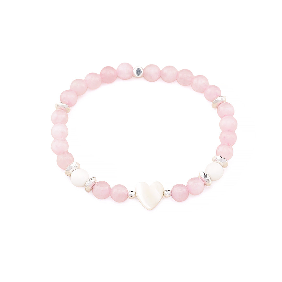 A beaded stretch bracelet featuring light pink round beads, a white heart-shaped bead, and small silver metallic spacer beads, displayed on a clean white background.